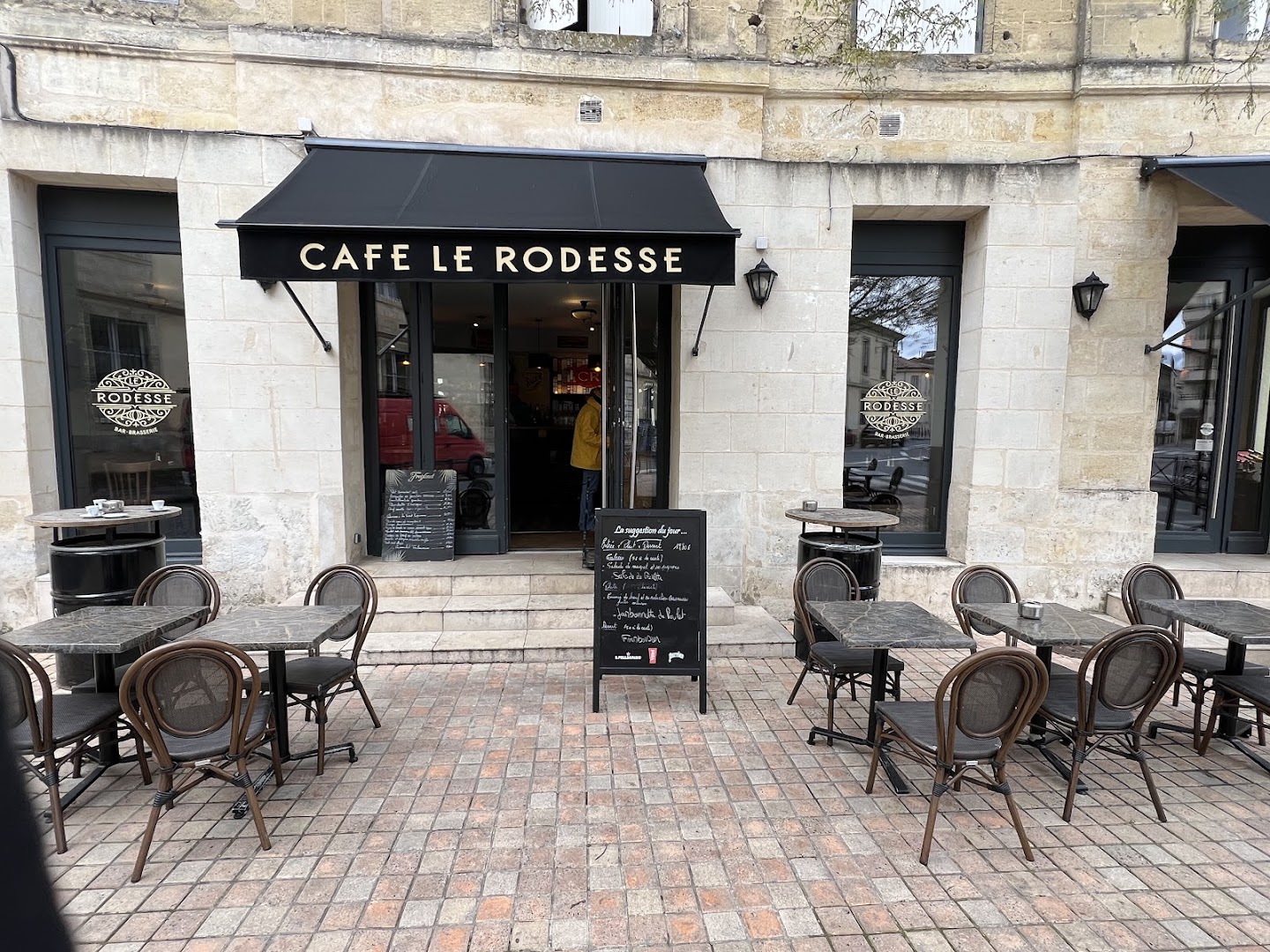 Façade, enseigne et terrasse du Café Rodesse sur la place