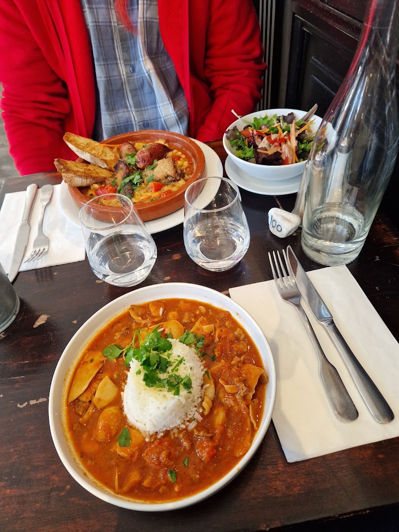 Deux plats mijotés, bol de salade, verres et bouteille sur une table
